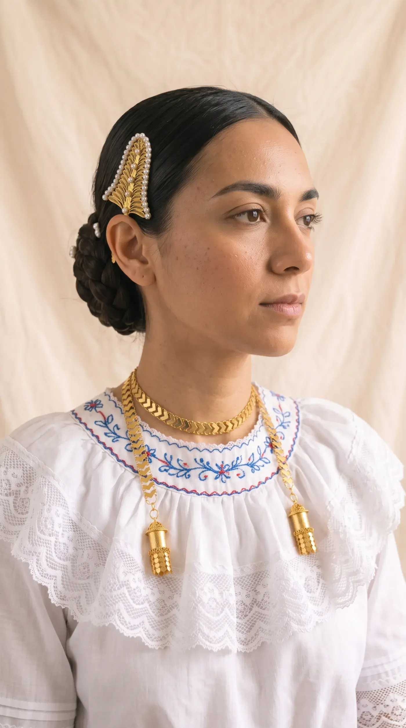 Modelo empollerada luciendo la pajuela con perlas en un moño trenzado y la cadena bruja con sus dos dijes, piezas de Prendas By Felicity.
